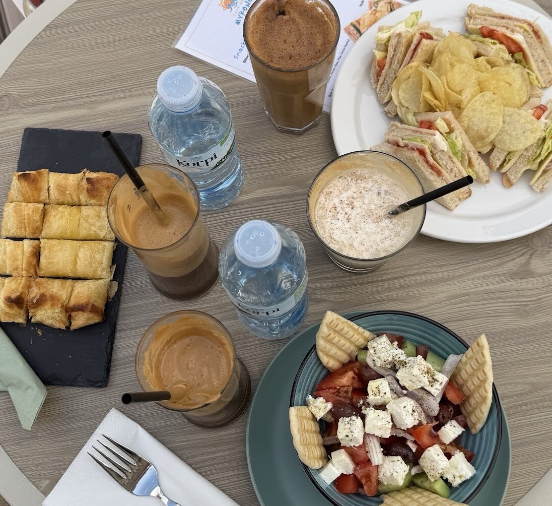 Gedeckter Tisch mit Snacks, Frappé, griechischem Salat und Clubsandwich